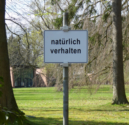 Schild mit folgender Anweisung: Natürlich verhalten.