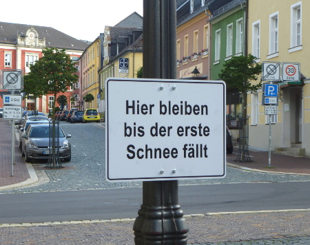 Schild mit folgender Anweisung: Hier bleiben bis der erste Schnee fällt.