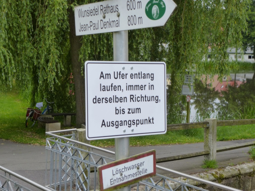 Schild mit folgender Anweisung: Am Ufer entlang laufen, immer in der derselben Richtung, bis zum Ausgangspunkt.